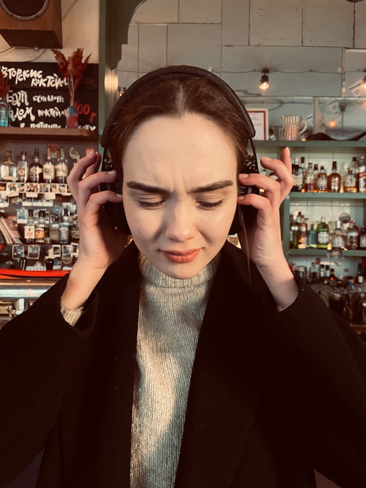 Portrait Of Woman In Cafe Putting On Headphones