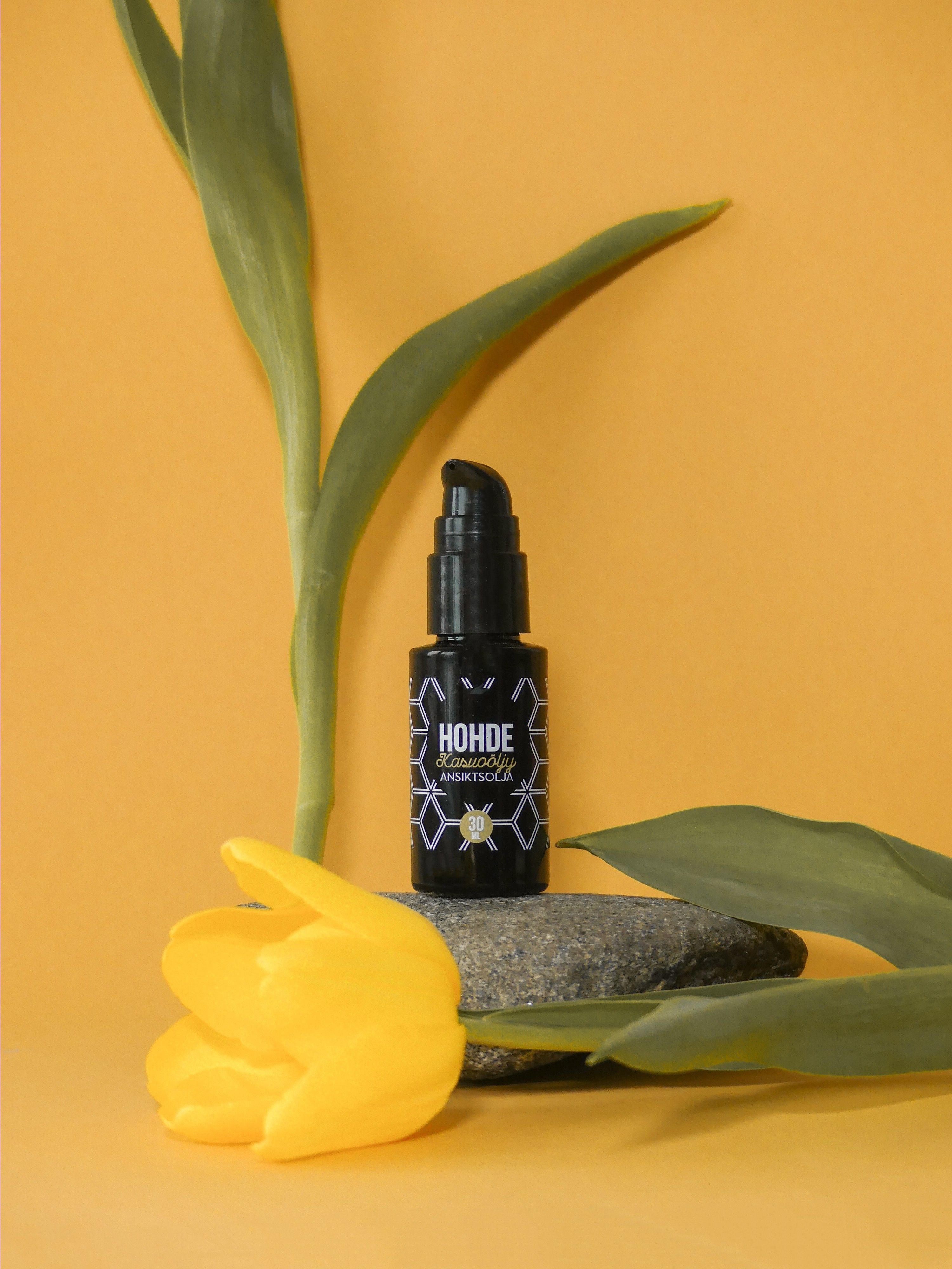 Green Vitamin C ampoule bottle resting among fresh leaves