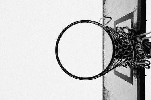 A bold black-and-white low-angle shot of a basketball hoop shot from below.
