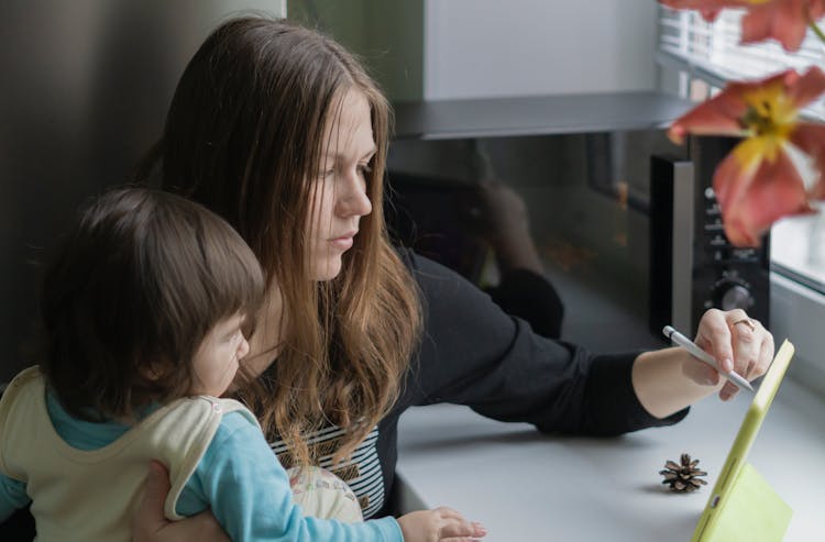 Woman Working On Tablet Holding Toddler