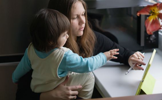 A mother and child interacting with a tablet, emphasizing parenting and technology.