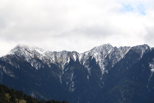 Stunning view of a snow-covered mountain range under a cloudy sky, perfect for nature enthusiasts.