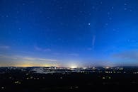 城市上空是充满活力的夜空，下方灯火通明，非常适合天文爱好者