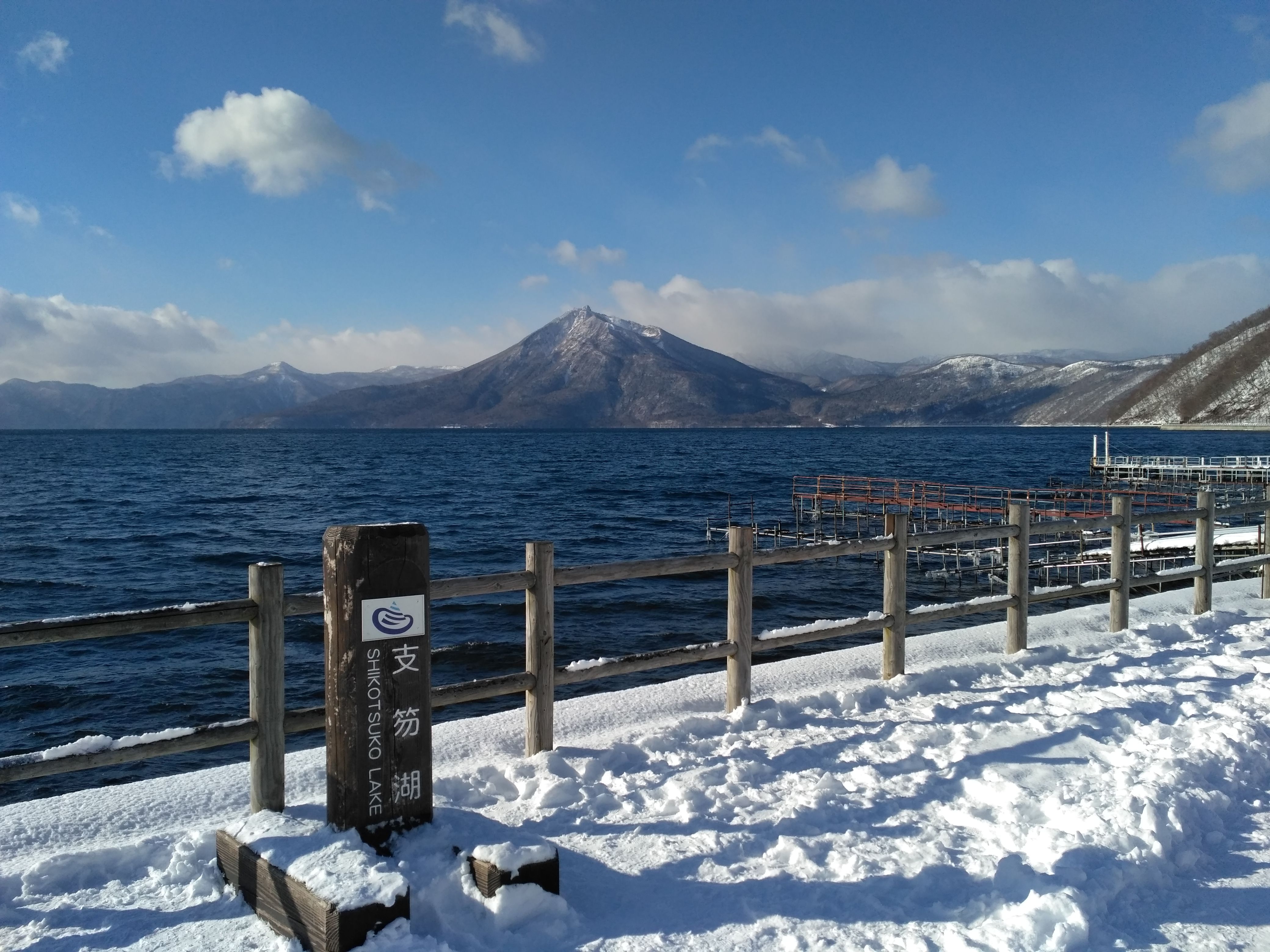 Scenic view of Shikotsu Lake with snow-covered mountains and winter landscape.