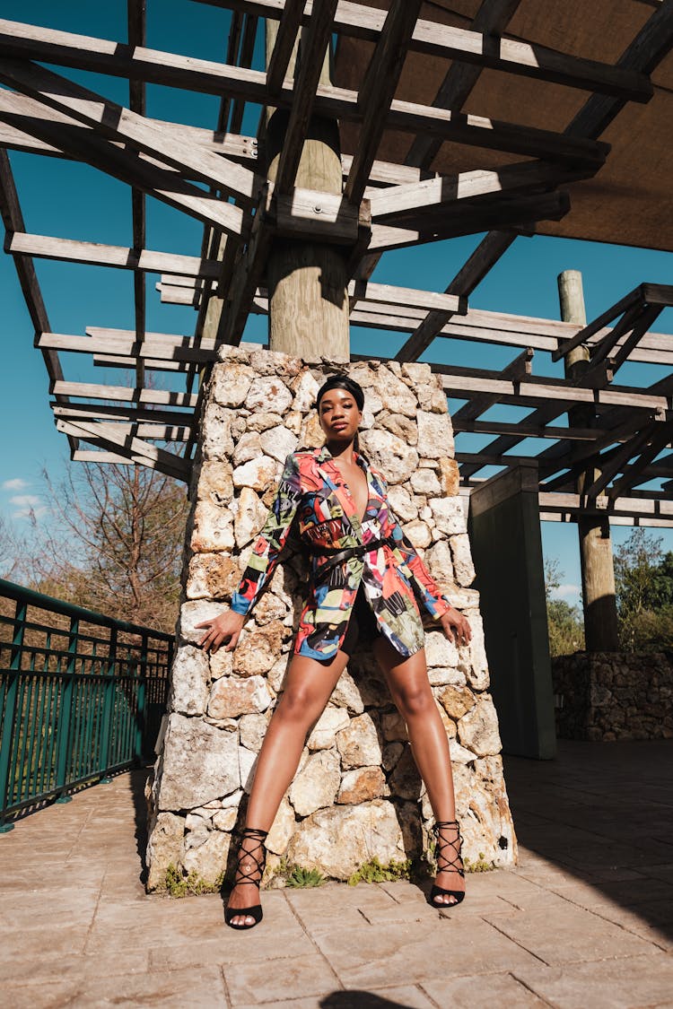 Woman In Colorful Blazer Standing Beside The Stone Wall