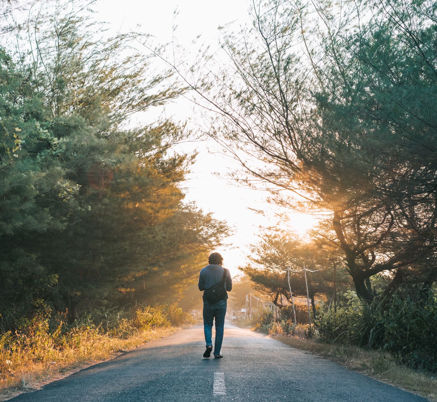 Man walking down a tree-lined path at sunrise, an exit ramp from the sub-5 label