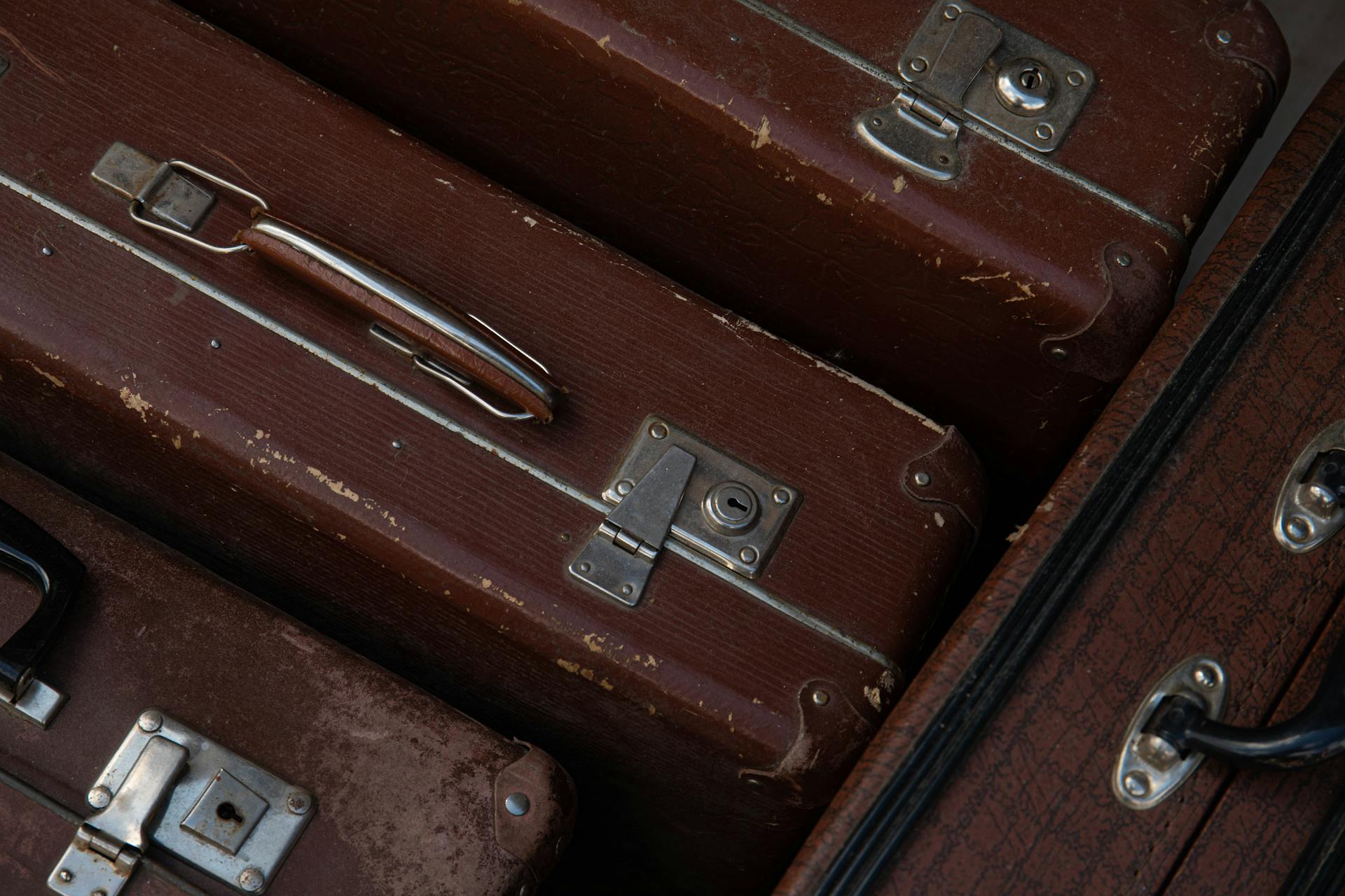 Close-up of vintage brown suitcases showing leather texture and metal locks.