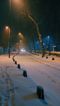 A serene snow-covered street in Istanbul illuminated by street lamps at night.