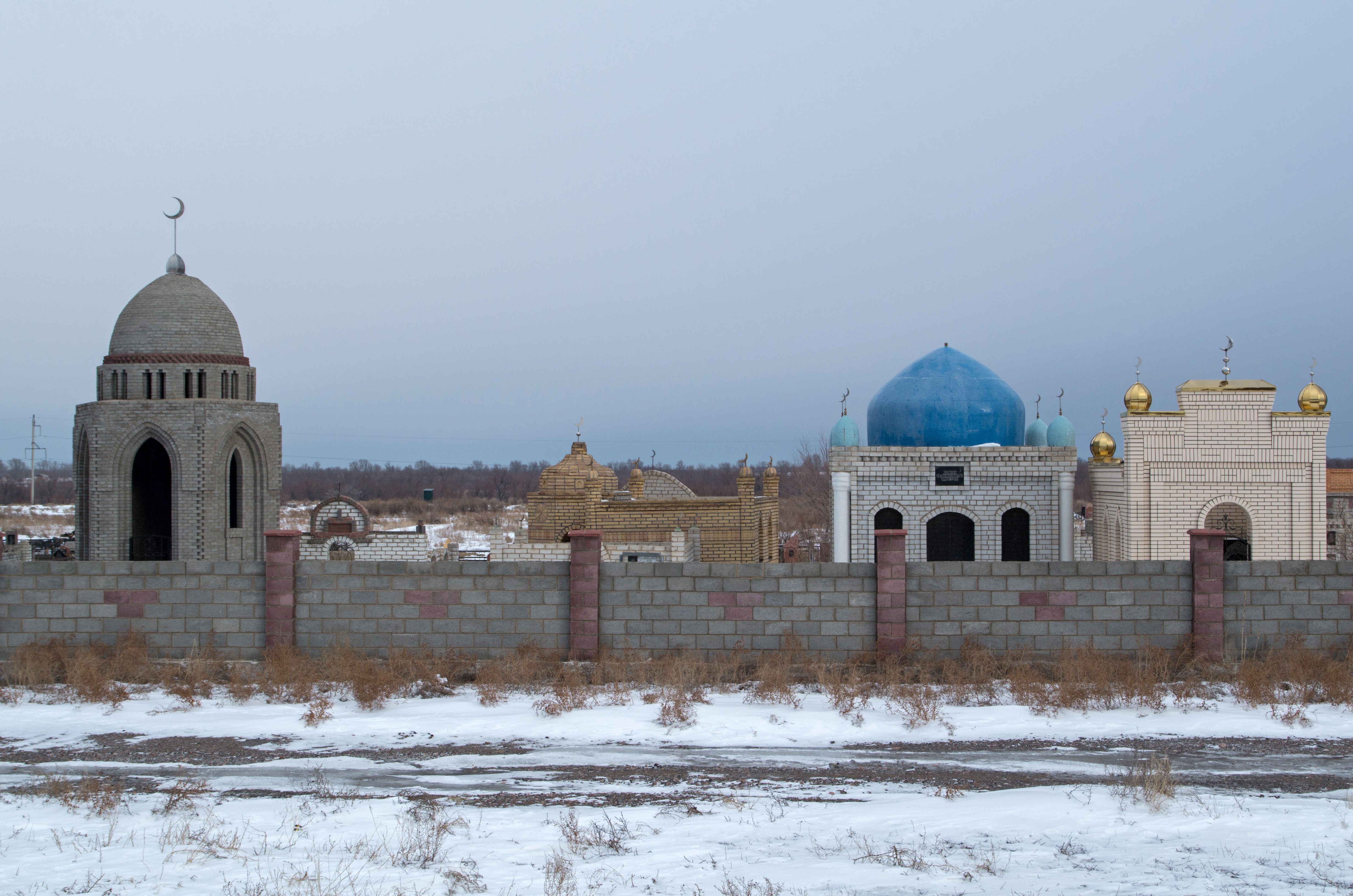 Snow-covered mausoleums in Nura, Kazakhstan, showcasing intricate architecture.