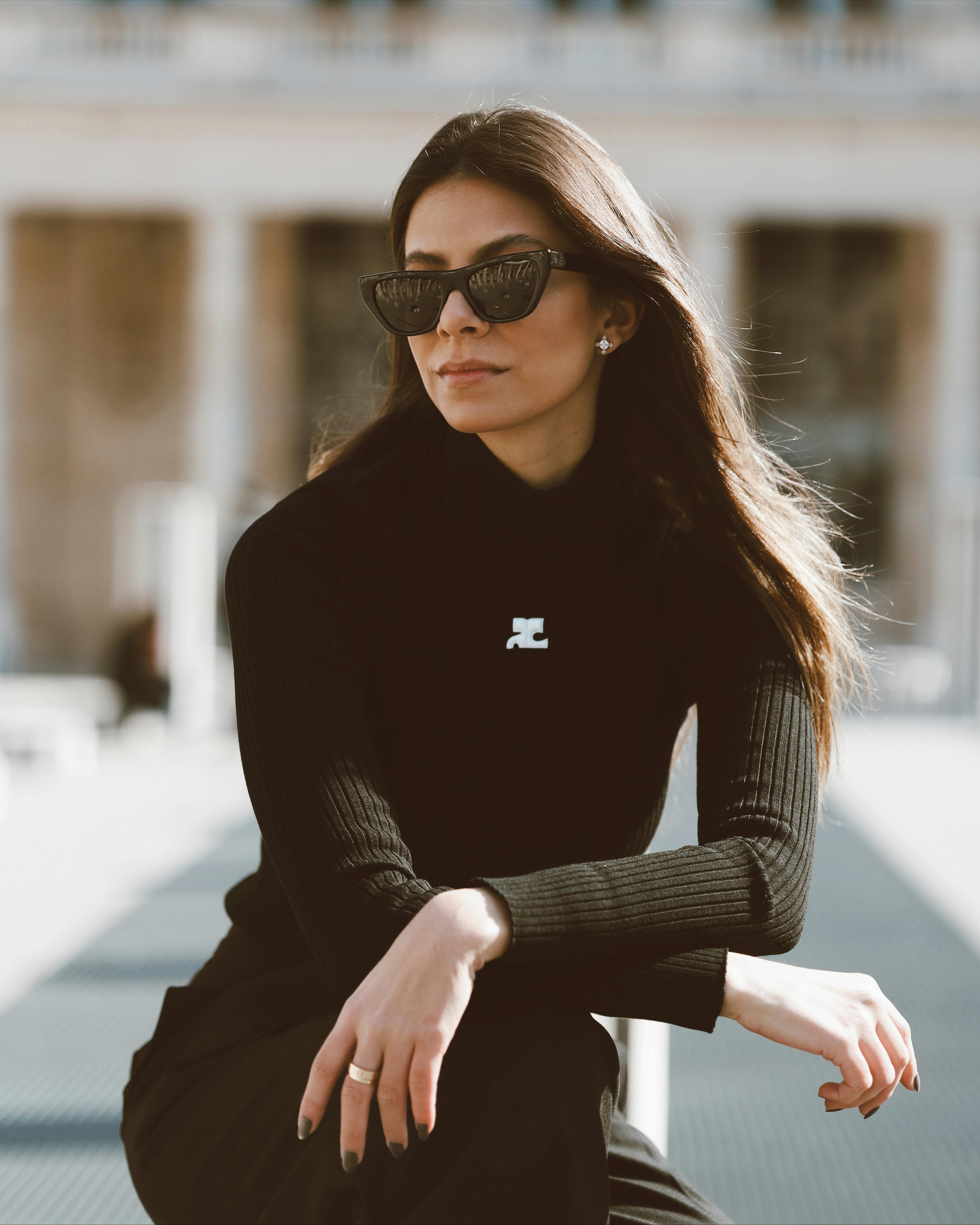 Stylish woman wearing sunglasses and black clothing posing outdoors in Paris.
