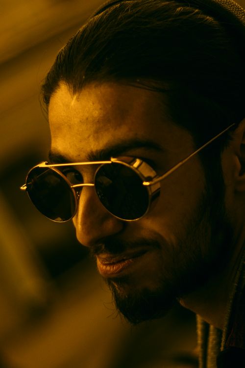 Free Close-up of a stylish man with sunglasses, smiling subtly in an artistic portrait. Stock Photo