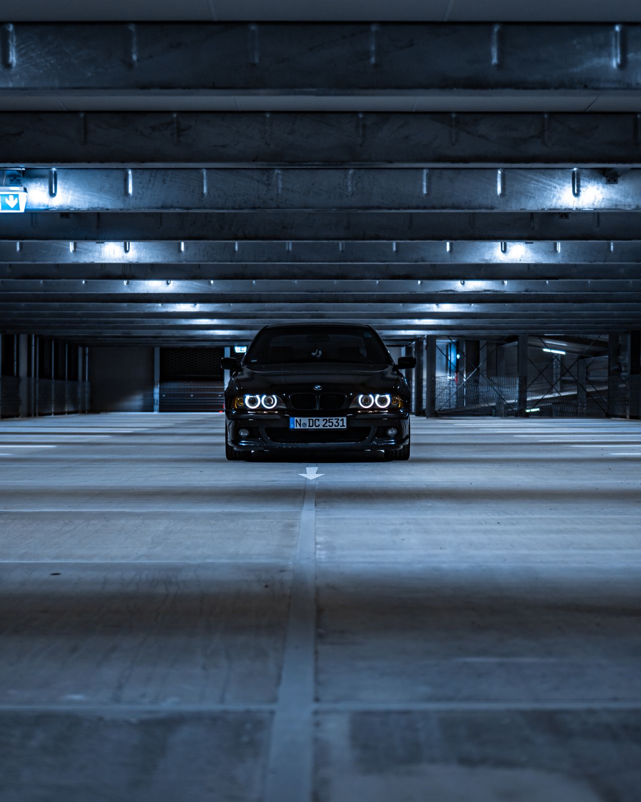 garage-gallery-moody-concrete Black car parked in a moody underground parking garage with concrete columns