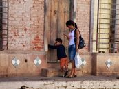 A mother and child at a rustic entrance on a sunny day, highlighting urban life.