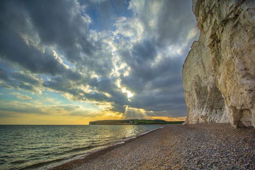 Gratis Beige And Grey Rock On The Seashore Photograph Foto Stok