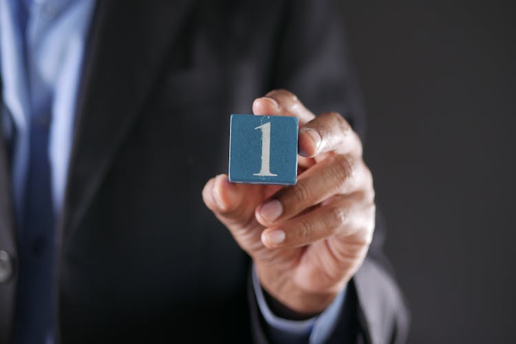 A Close-Up Shot Of A Person Holding A Block With A Number