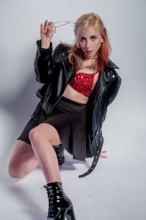Free Fashionable woman posing in edgy outfit with leather jacket and glasses, showcasing modern street style. Stock Photo