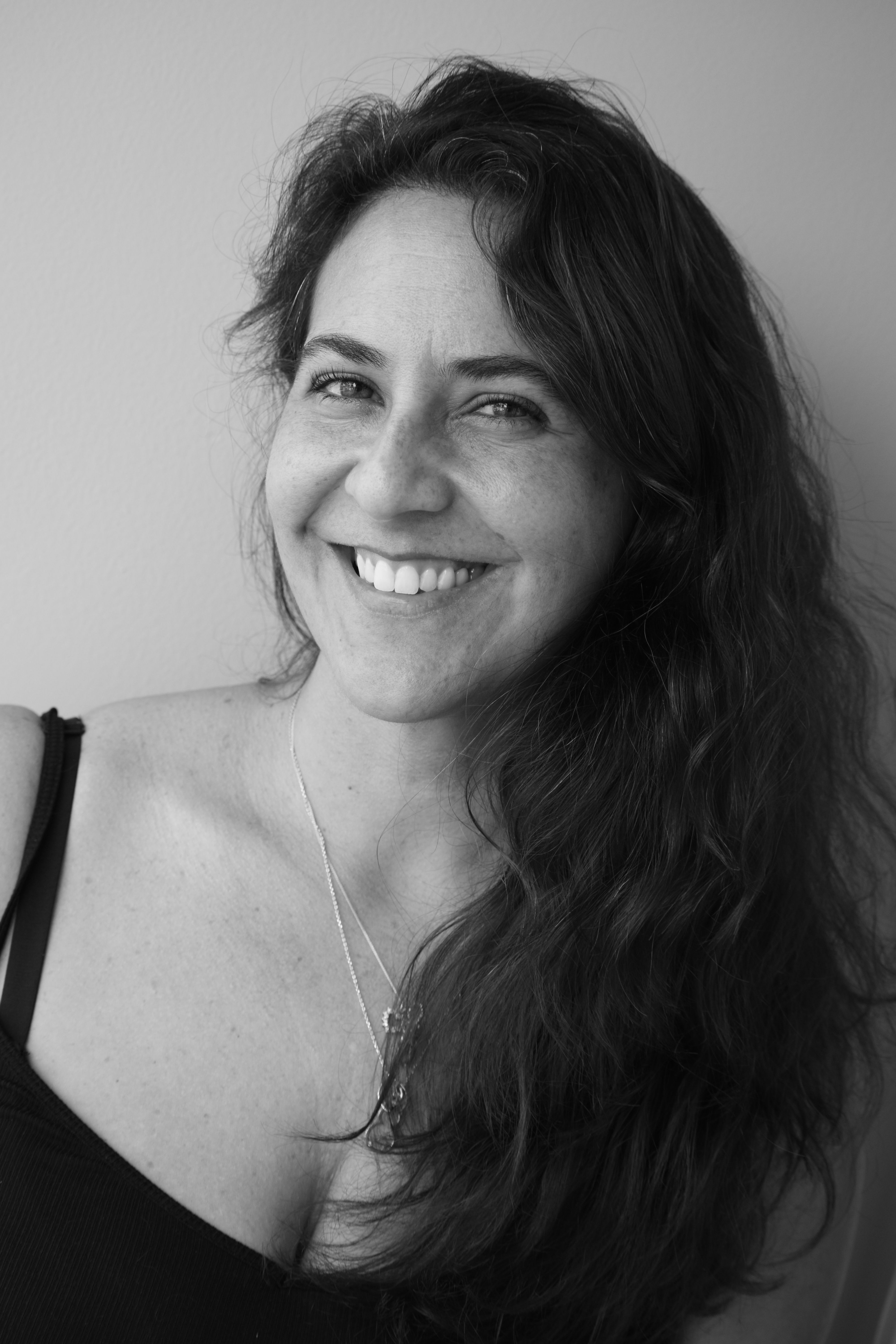 A captivating black and white portrait of a smiling woman with long hair.