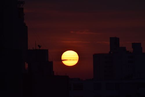 Free Stunning silhouette of city buildings against a vibrant sunset sky. Stock Photo