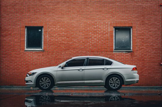 Side view of a silver sedan parked by a brick wall — photo by Kadir Akman on Pexels