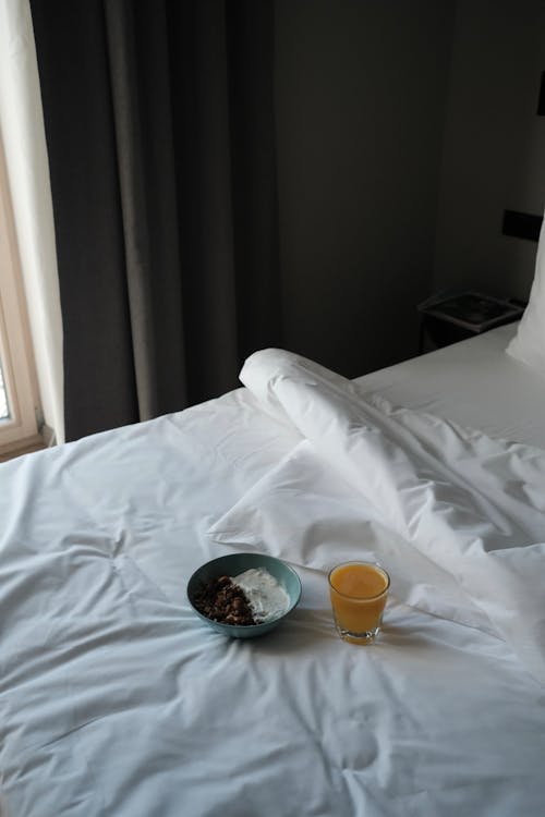Free Musli Bowl and Orange Juice on Bed Covers Stock Photo
