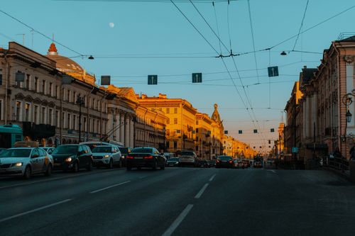 Free A bustling city street with historic architecture and moving traffic under the evening sky. Stock Photo