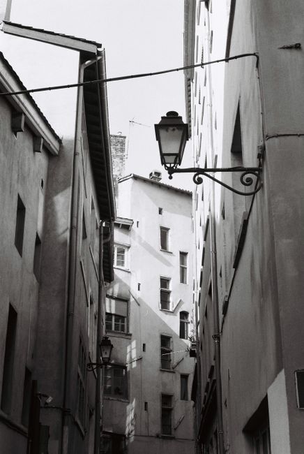 A striking black and white photo of a narrow alleyway in Lyon, capturing urban architecture.