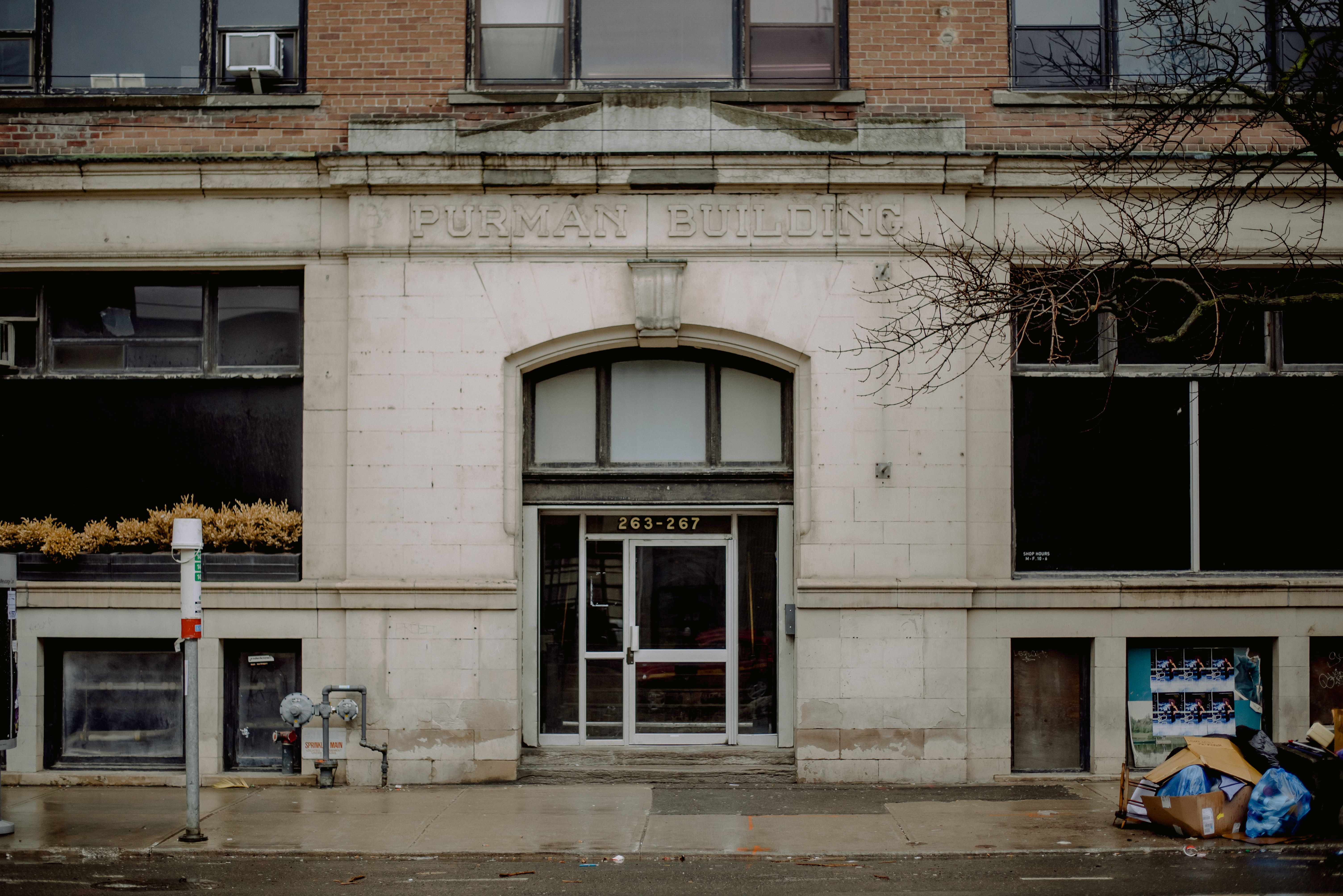 A historic abandoned building with a glass door and brick facade captured on a rainy day.