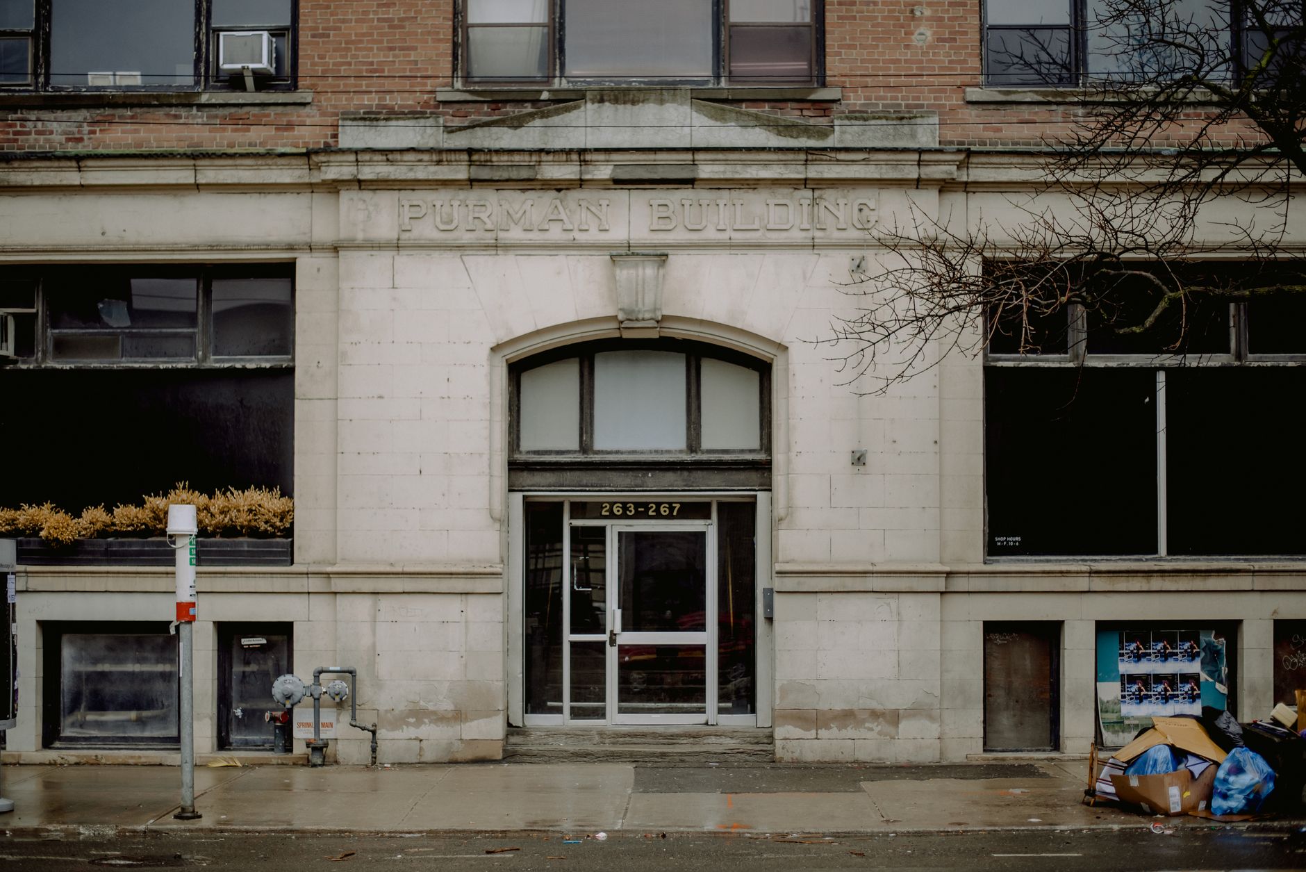 A historic abandoned building with a glass door and brick facade captured on a rainy day.
