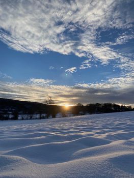 A serene winter landscape in Bolu, Türkiye, with snow-covered fields and a vibrant sunset.