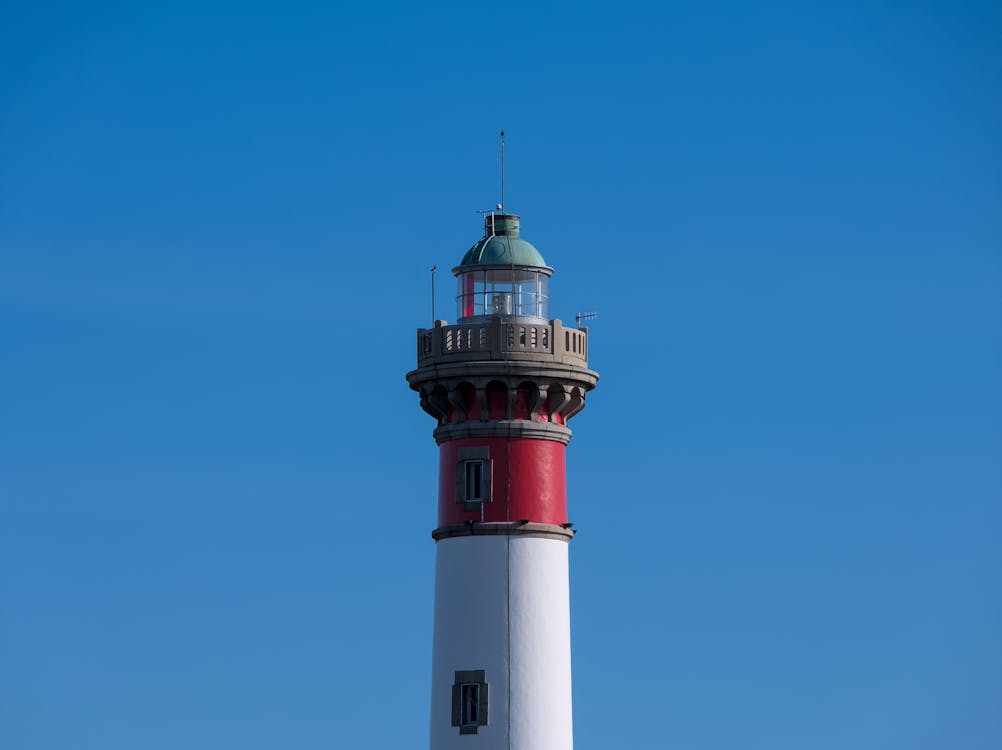Red and White Lighthouse Under Blue Sky