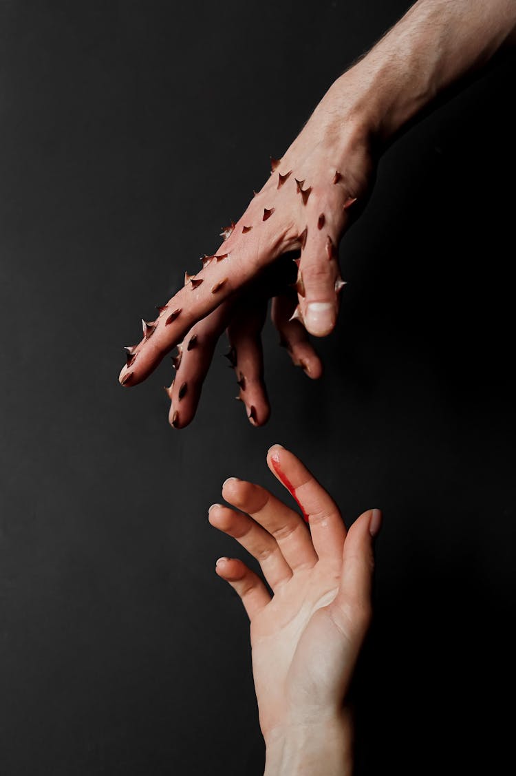 Hand Of Man Covered With Thorns And Bleeding Finger Of Woman Hand