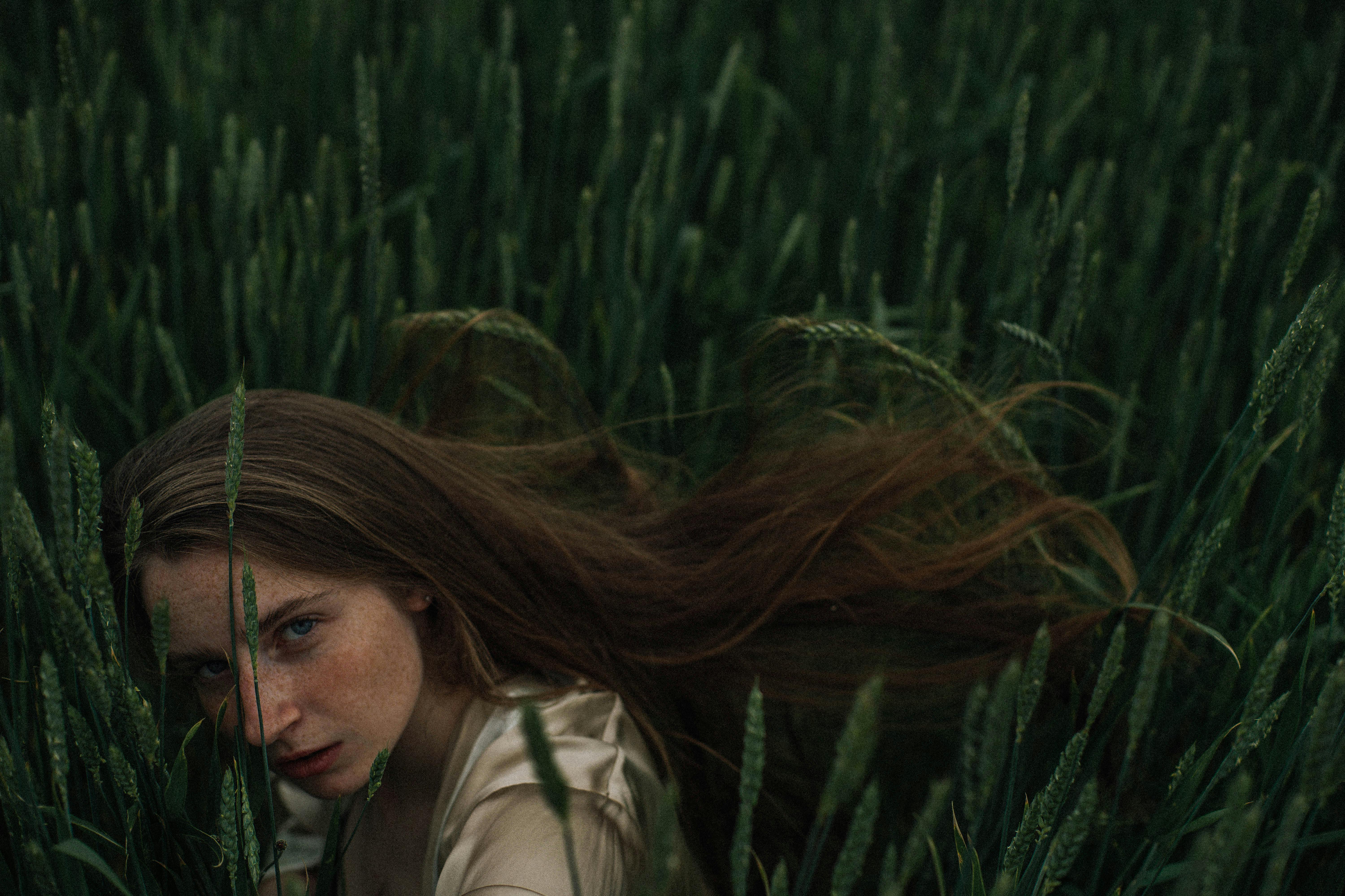 blond woman with freckled face hiding in crop field