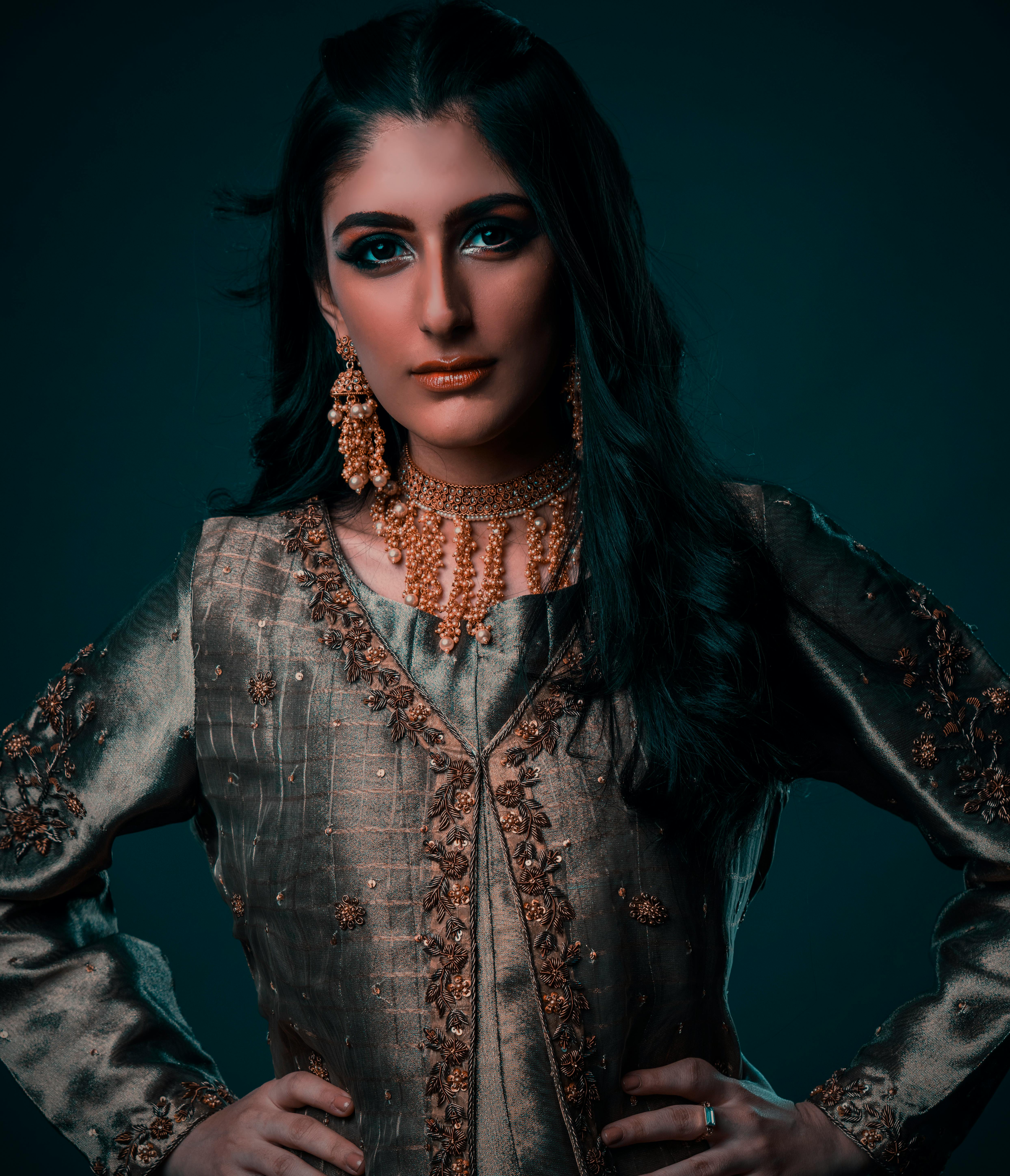 Portrait of a woman in traditional attire showcasing elegant jewelry against a blue background.