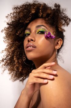 A captivating portrait of a woman with intricate and colorful eye makeup and floral accessory.