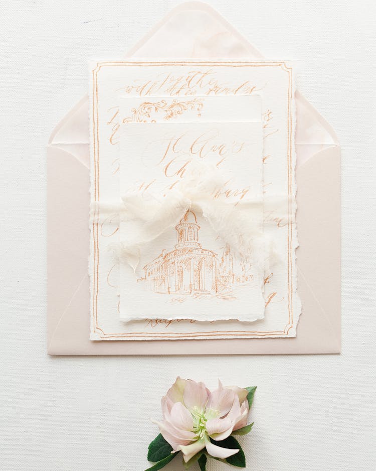 Stack Of Drawings On Envelope And Flower On Desk