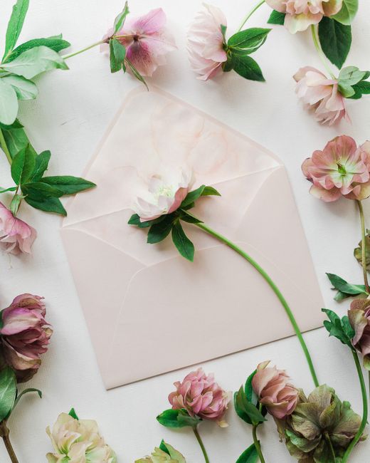 Delicate pink flowers and a soft envelope create a romantic flat lay design.