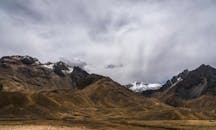 在多云的天空下，崎岖的山脉与白雪皑皑的山峰令人惊叹，尽显自然之美