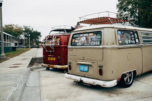 Classic Volkswagen vans with stickers parked on a street, showcasing vintage charm.