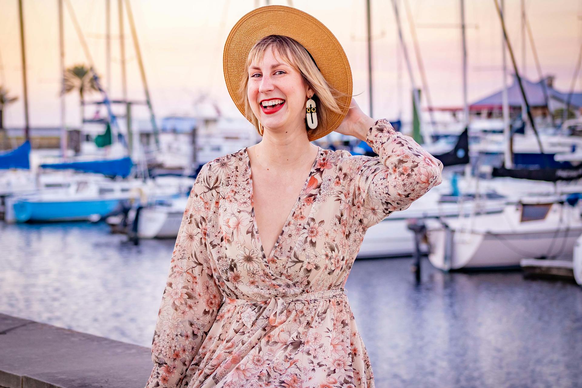 A joyful woman in a floral dress enjoying a sunny day at Sanford Marina with boats and palm trees in the background.