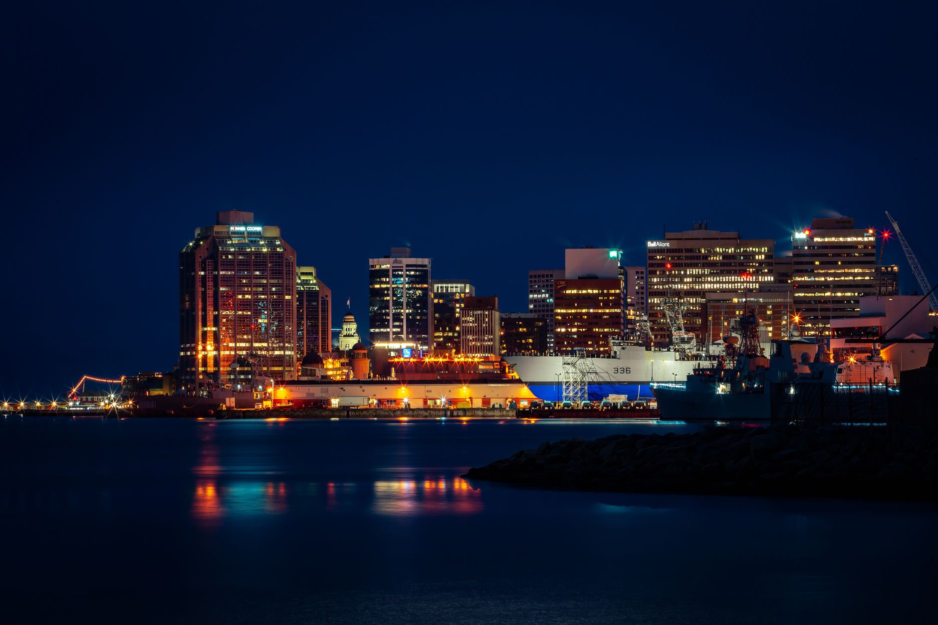 Illuminated Halifax skyline along the waterfront, featuring striking city lights reflected in the harbor at night.