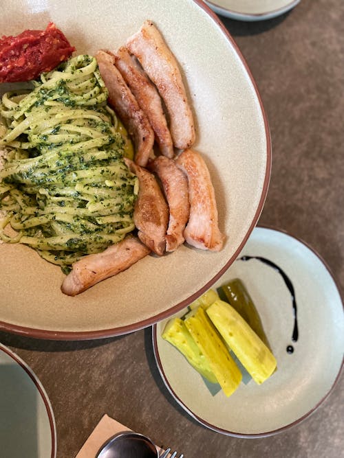 Green Pasta With Meat and Cucumbers on Ceramic Plate