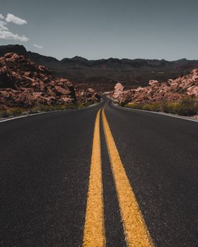 Desert highway through rocky terrain in Nevada, USA, with clear blue skies.