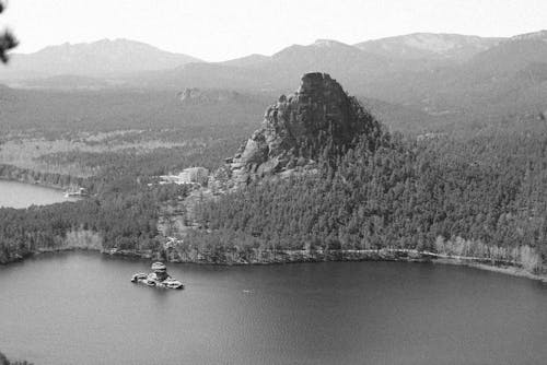Grayscale Photo of Rock Formation on Forest Near Body of Water