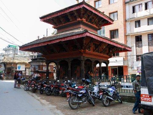 Free A pagoda-style temple surrounded by motorcycles in a bustling city street, capturing urban life. Stock Photo