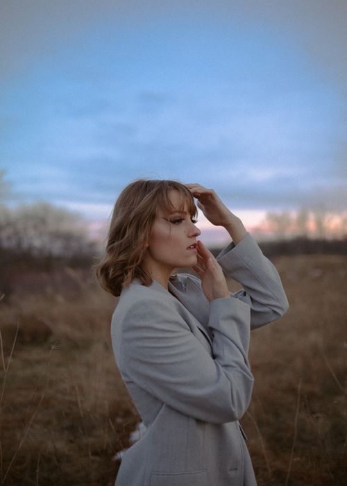 Free Elegant woman with blonde hair stands pensively in an Iowa meadow at twilight, capturing the serene atmosphere. Stock Photo