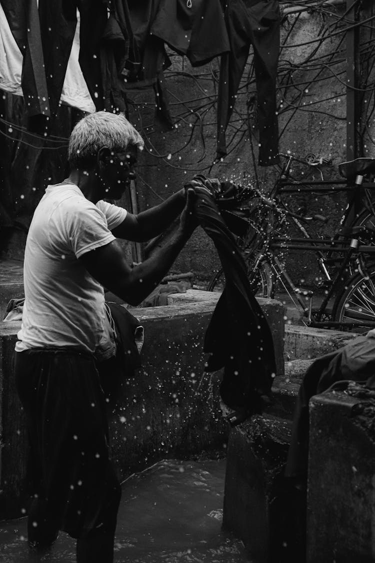 Grayscale Photograph Of A Man Washing Clothes