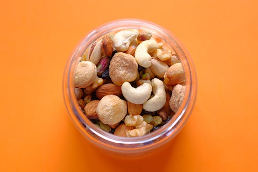 Close-up of a mix of nuts in a clear container against an orange background.