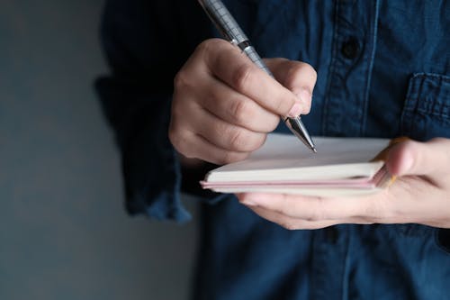 Close-Up Shot of a Person Writing on a Notebook