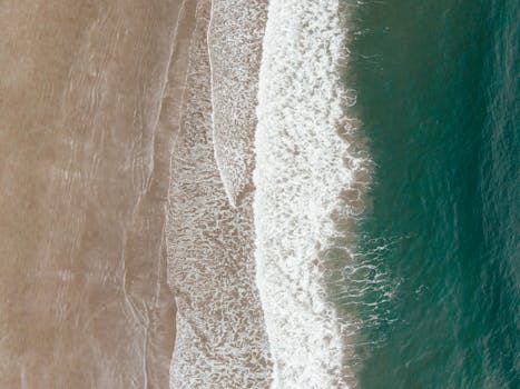 Stunning aerial view of waves crashing on a sandy beach in Tofino, BC, Canada.