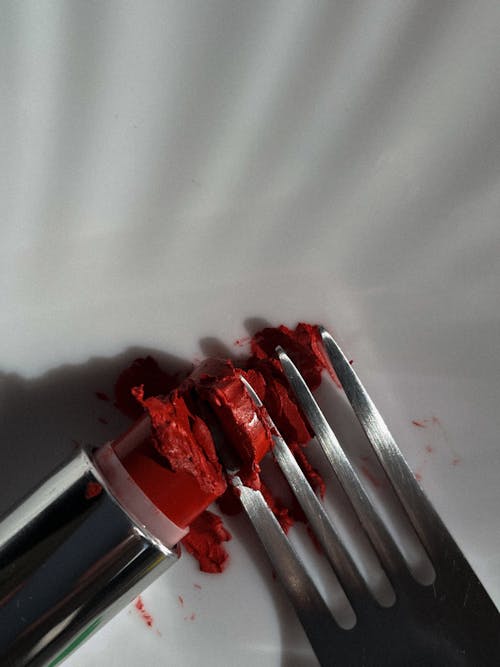 Close-Up Photo of a Lipstick with a Stainless Fork